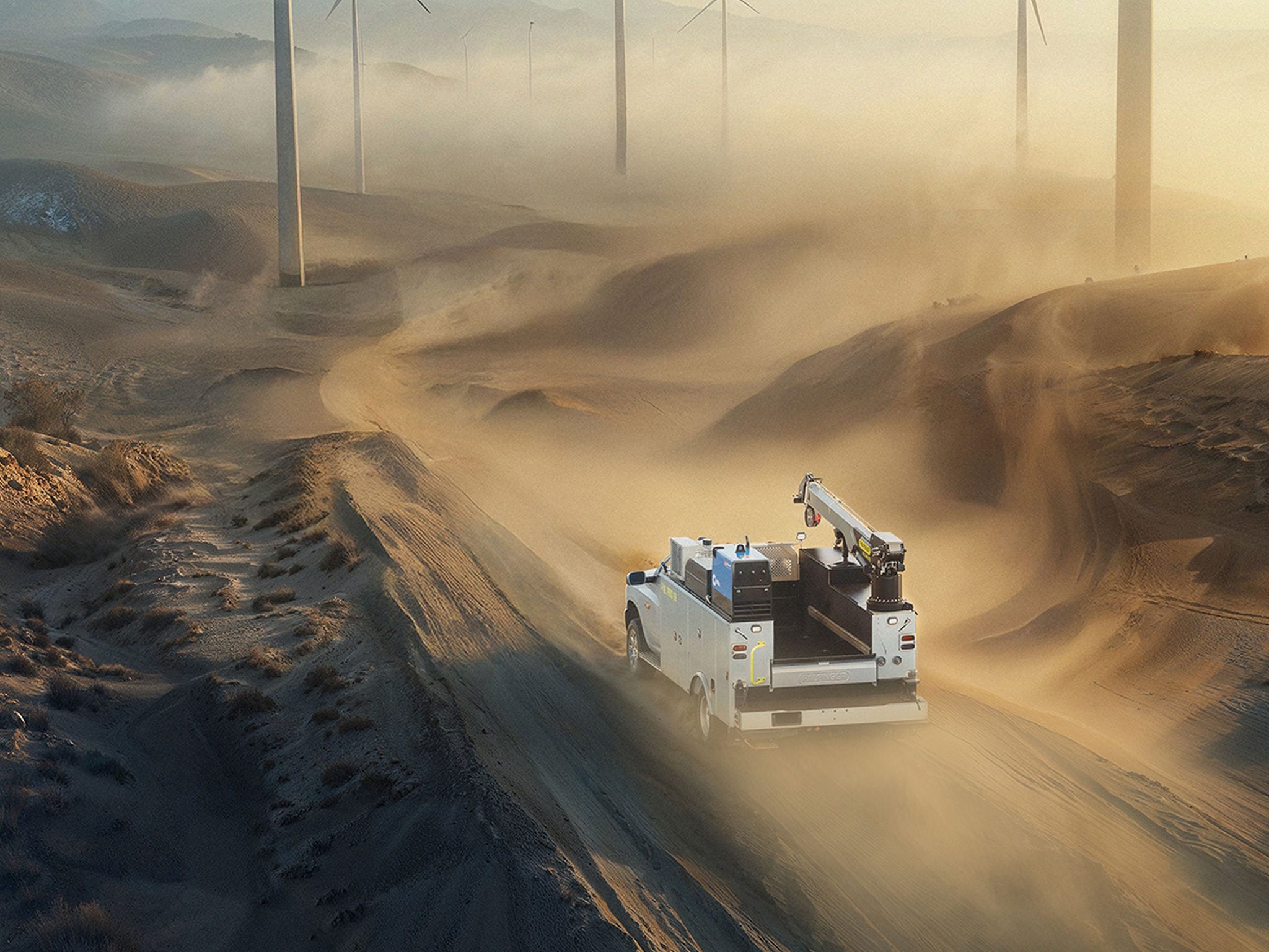 Industrial vehicle operating in a vast desert landscape, viewed from above, emphasizing scale, power, and environmental context.